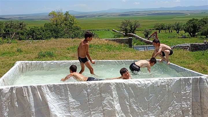 Kars'ta çocuklar serinlemek için traktör römorkunu havuz yaptı